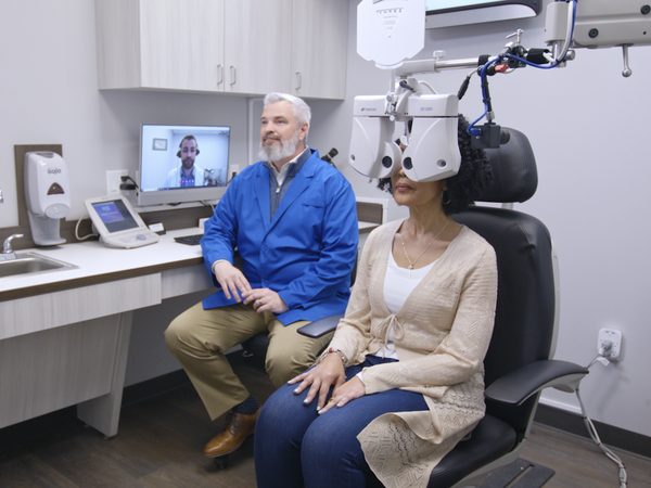 Patient sitting with doctor looking through optometrist machinery