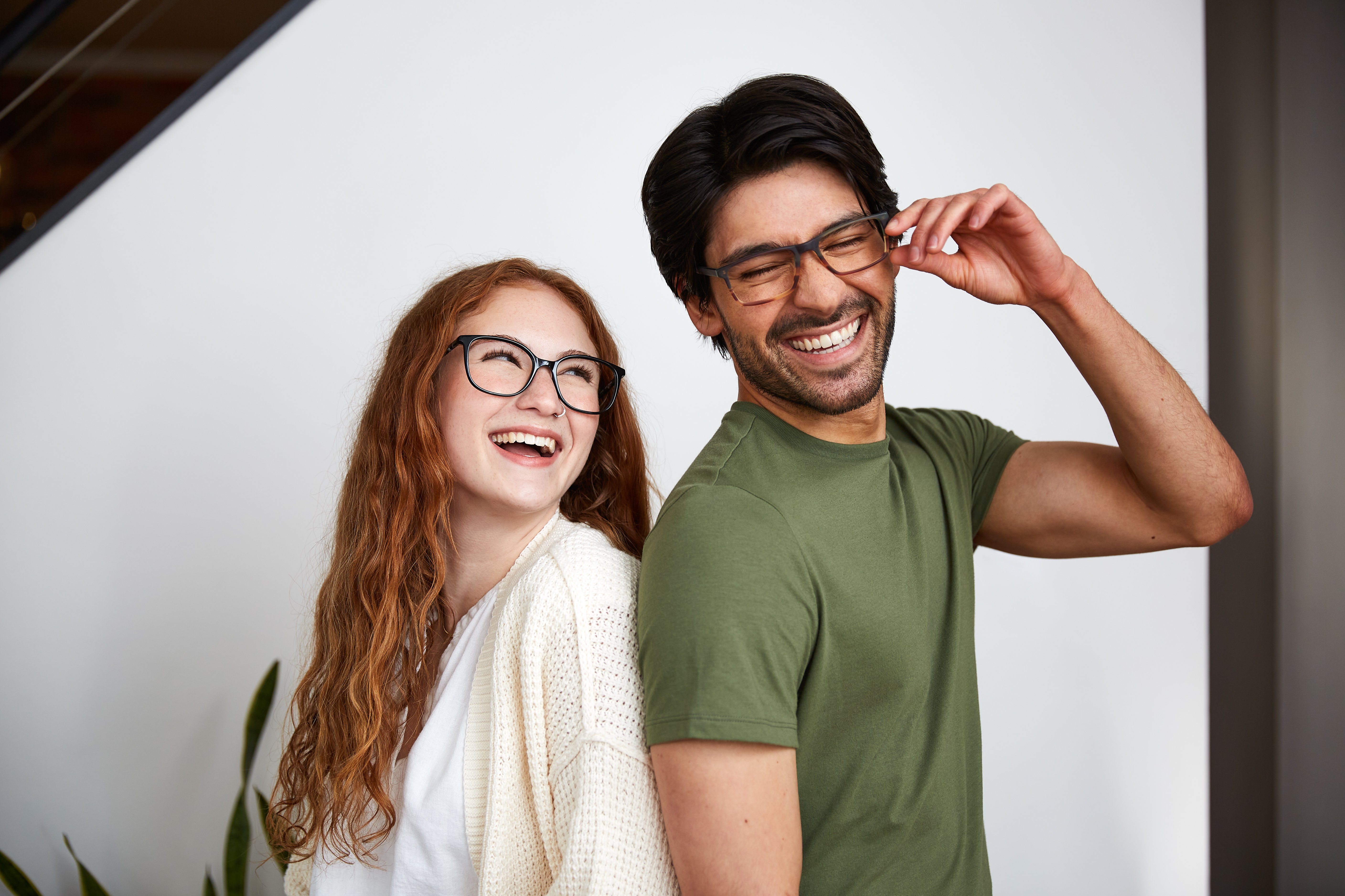 A man and a woman standing back to back wearing glasses